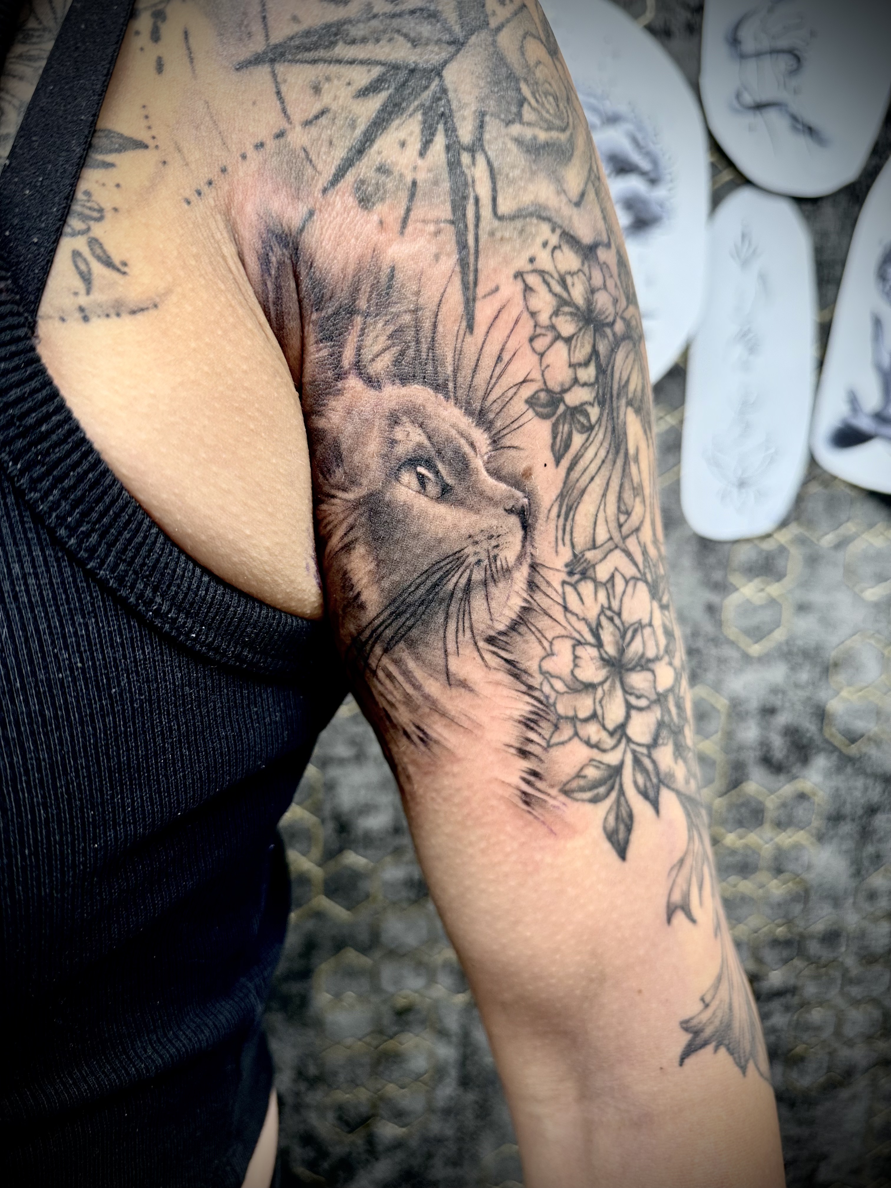 Tatouage symbolique réalisé chez L'Ascendant — chat et fleurs